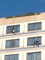 Window cleaners hanging from nothing but a piece of wood on a rope