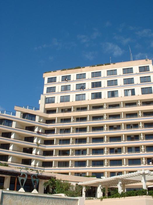 Window cleaners hanging from nothing but a piece of wood on a rope